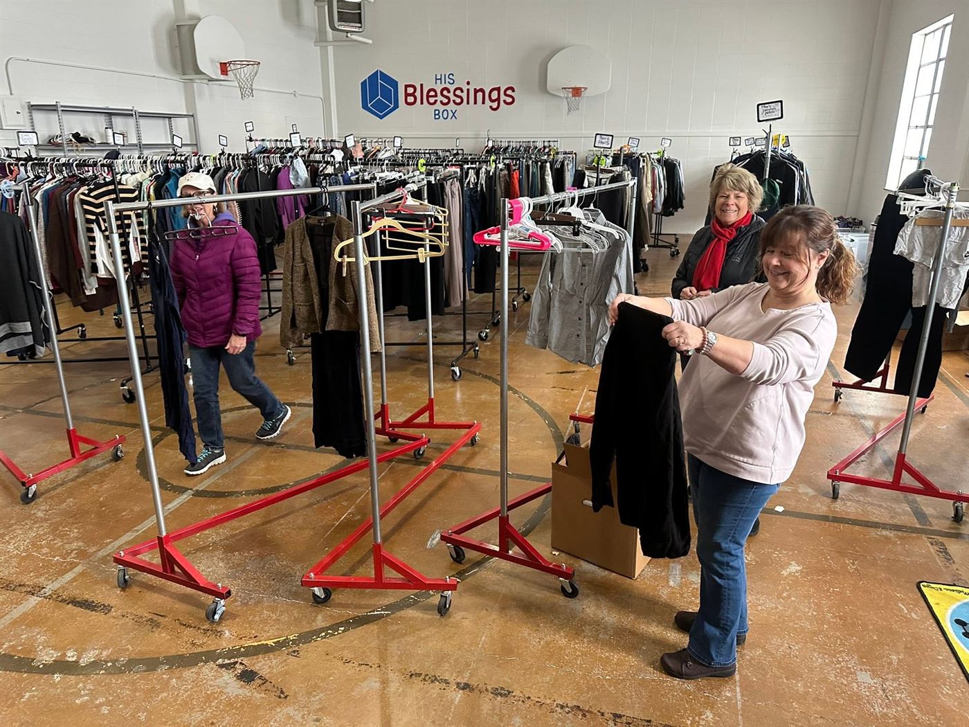 Neighbors browsing racks of free clothing at the clothing closet