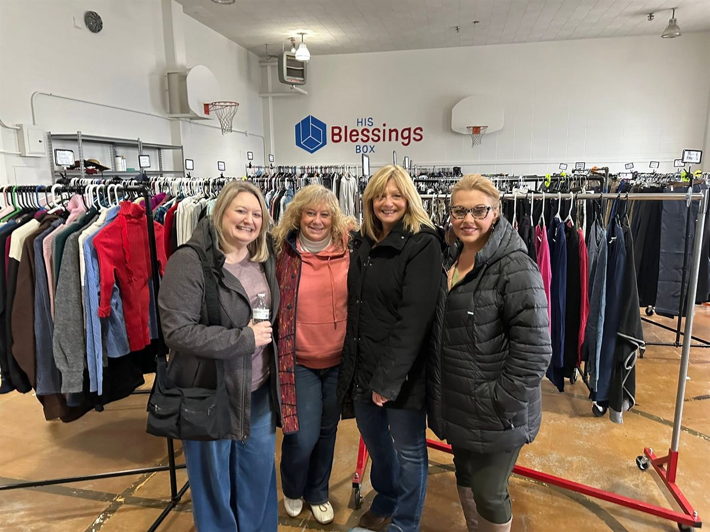 Volunteers helping guests find clothing among the racks