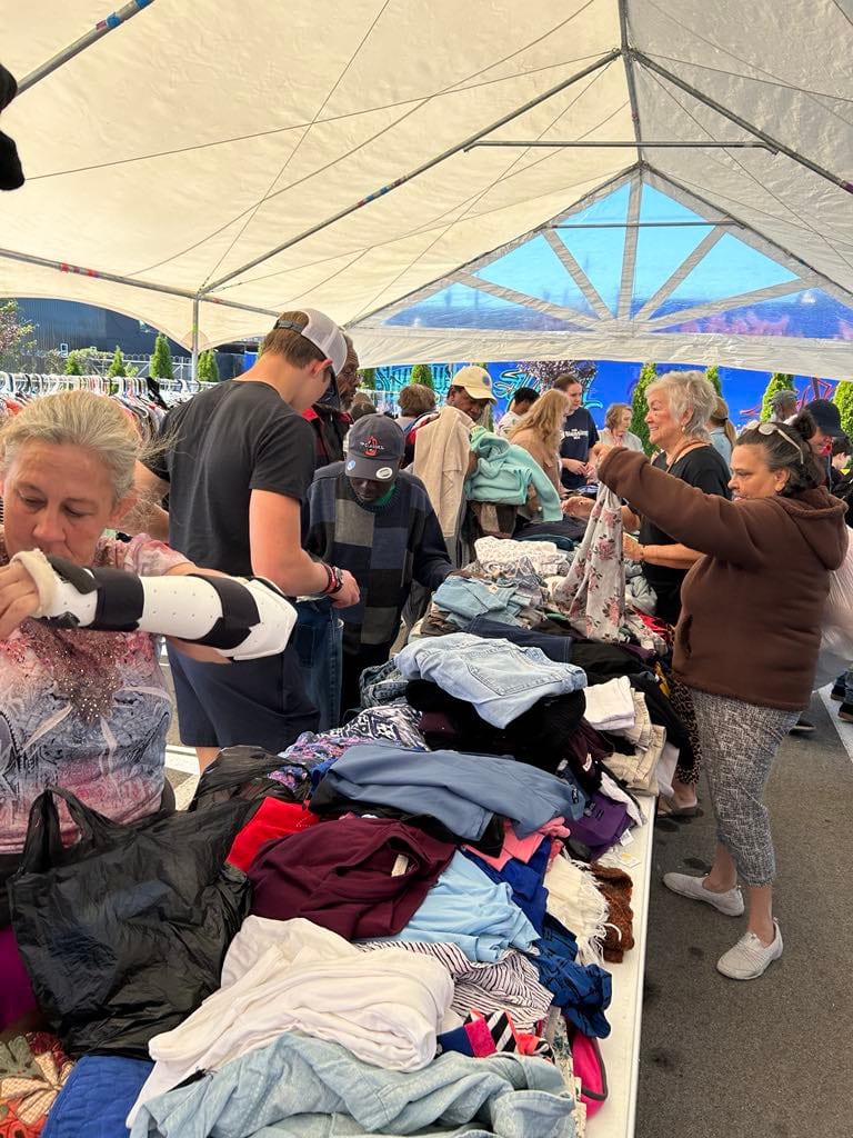 Tables of donated clothing set out for guests at a community day