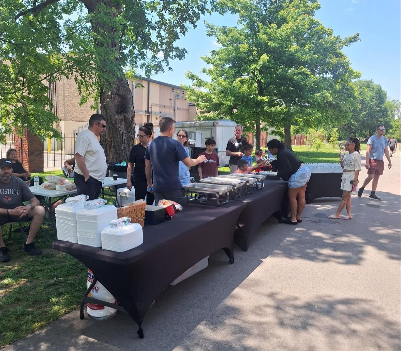 Volunteers serving food from tables under a tent at a community event