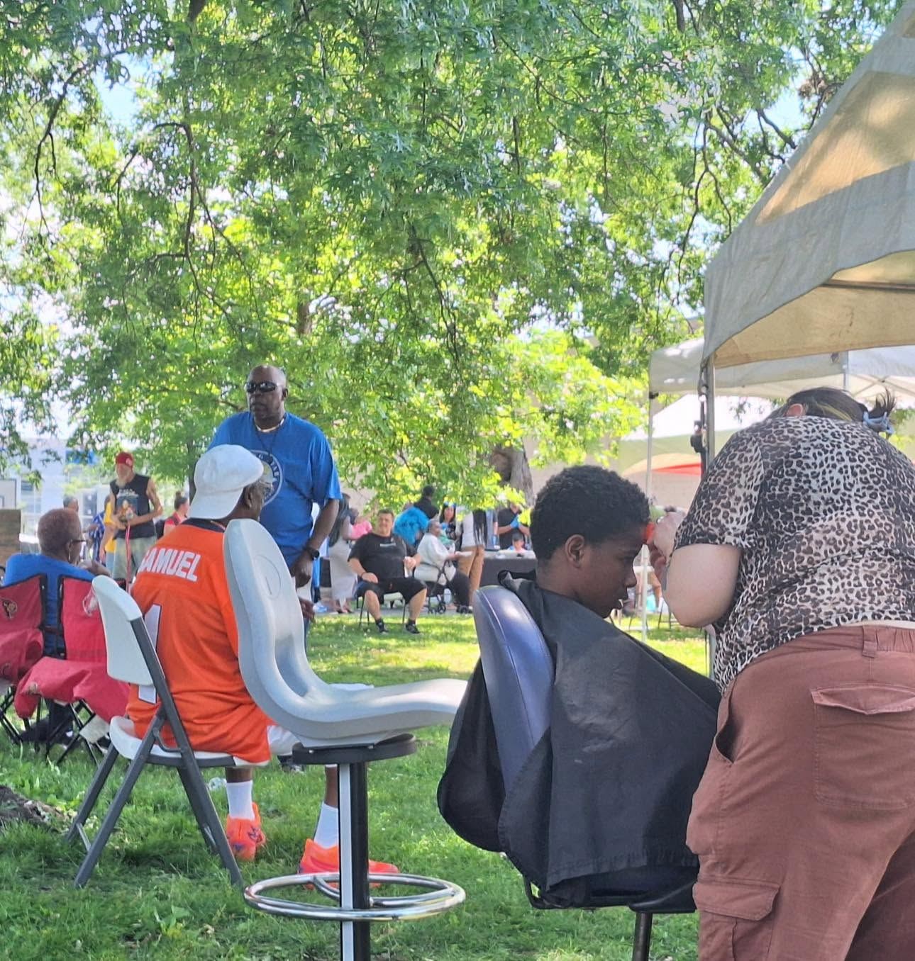 A barber giving a free haircut outdoors at a Louisville community day