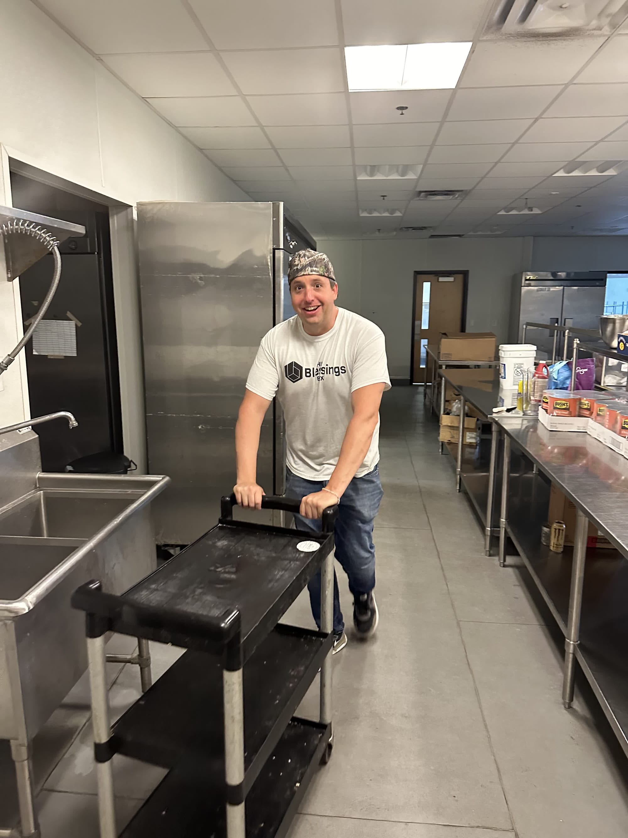 A His Blessings Box volunteer wheeling a cart through the kitchen before the Friday meal