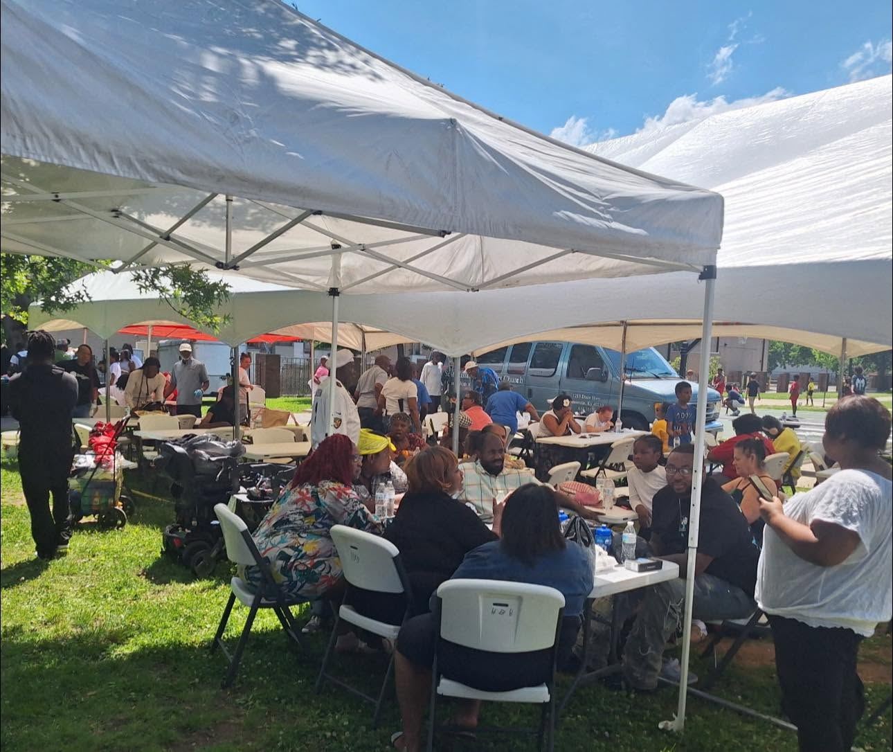 A community cookout in a Louisville park with tents and neighbors gathered