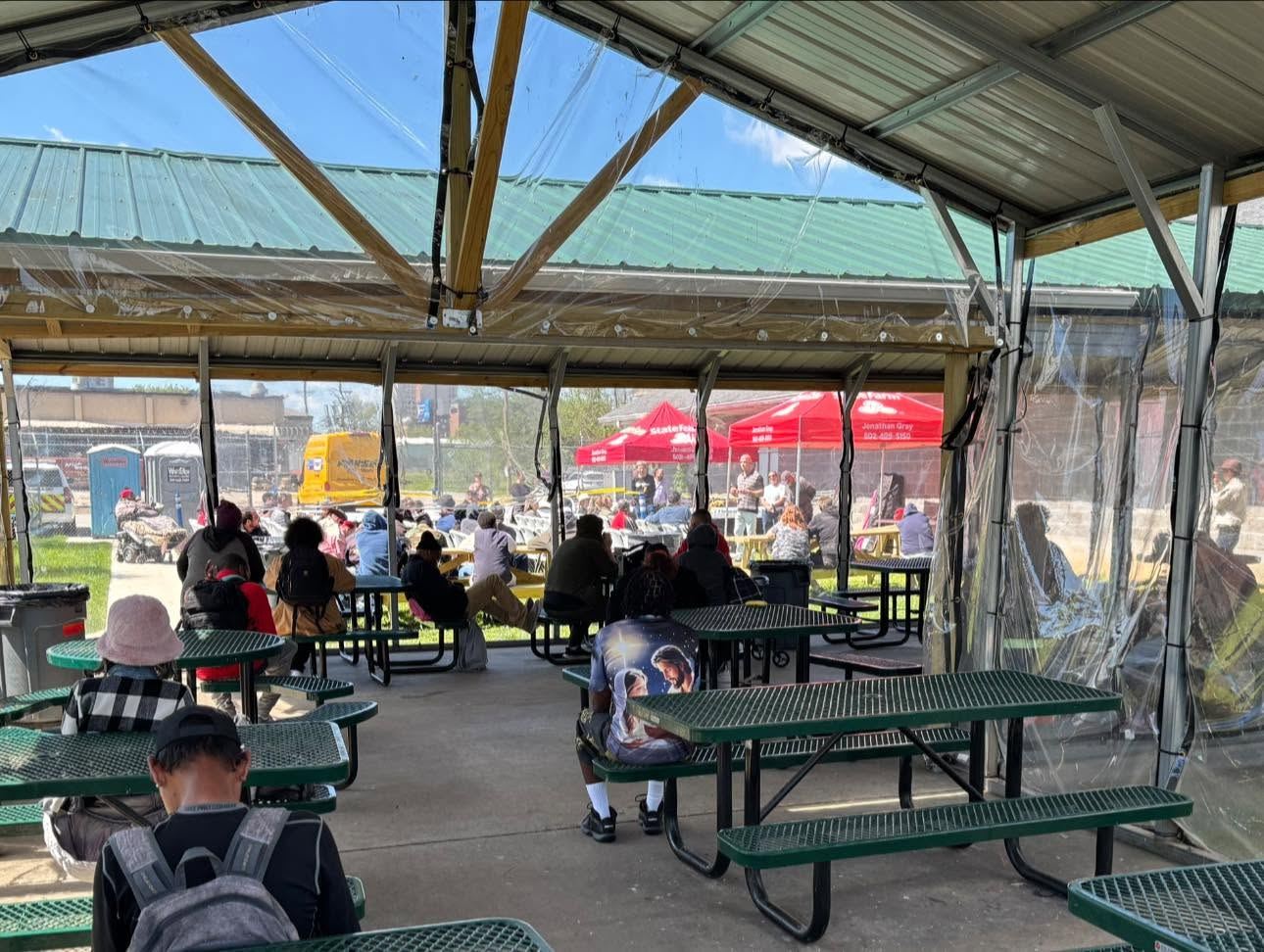 Guests eating together at picnic tables under a pavilion