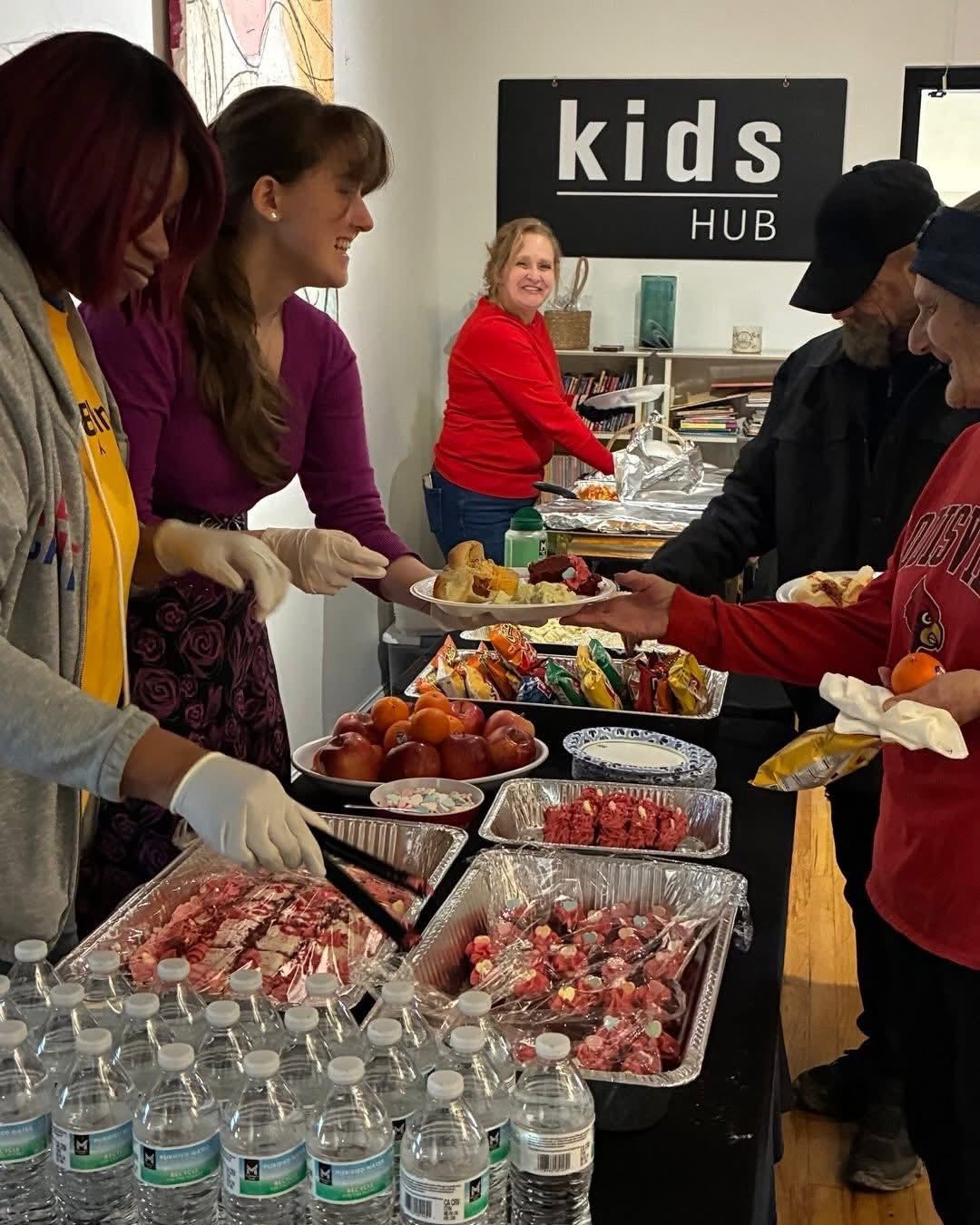 Volunteers plating food onto trays before guests arrive