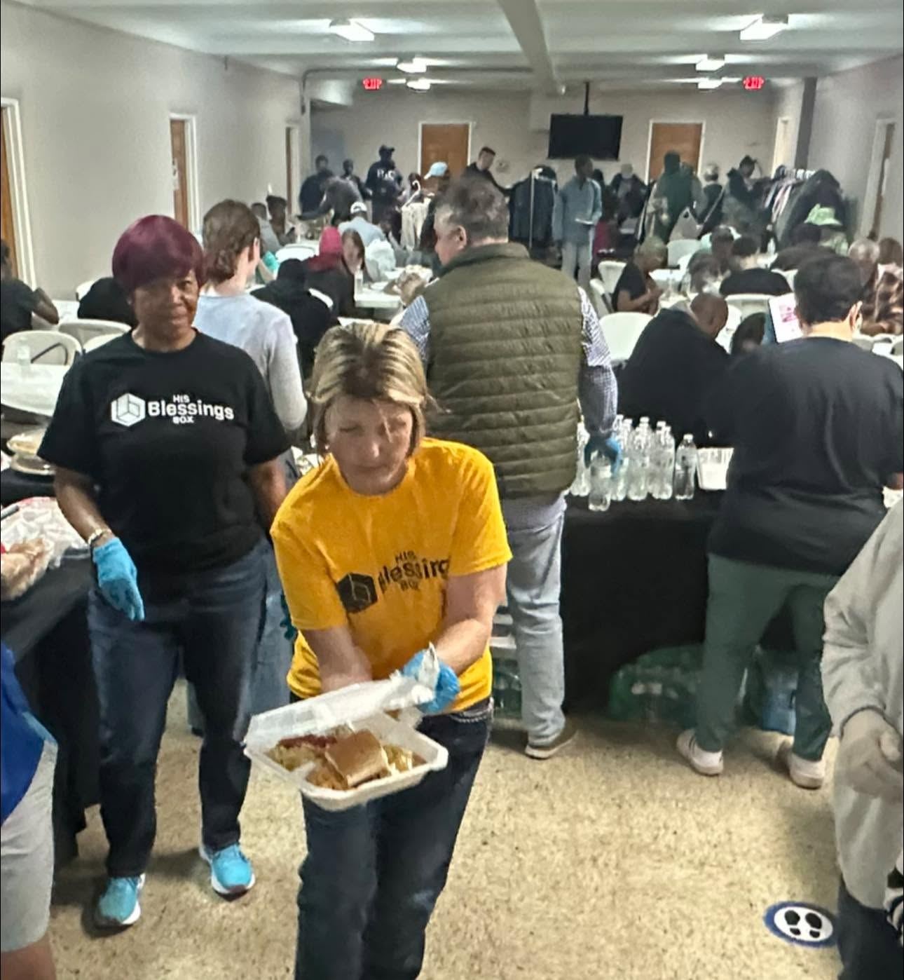 A volunteer handing a plate of food to a guest at the community meal