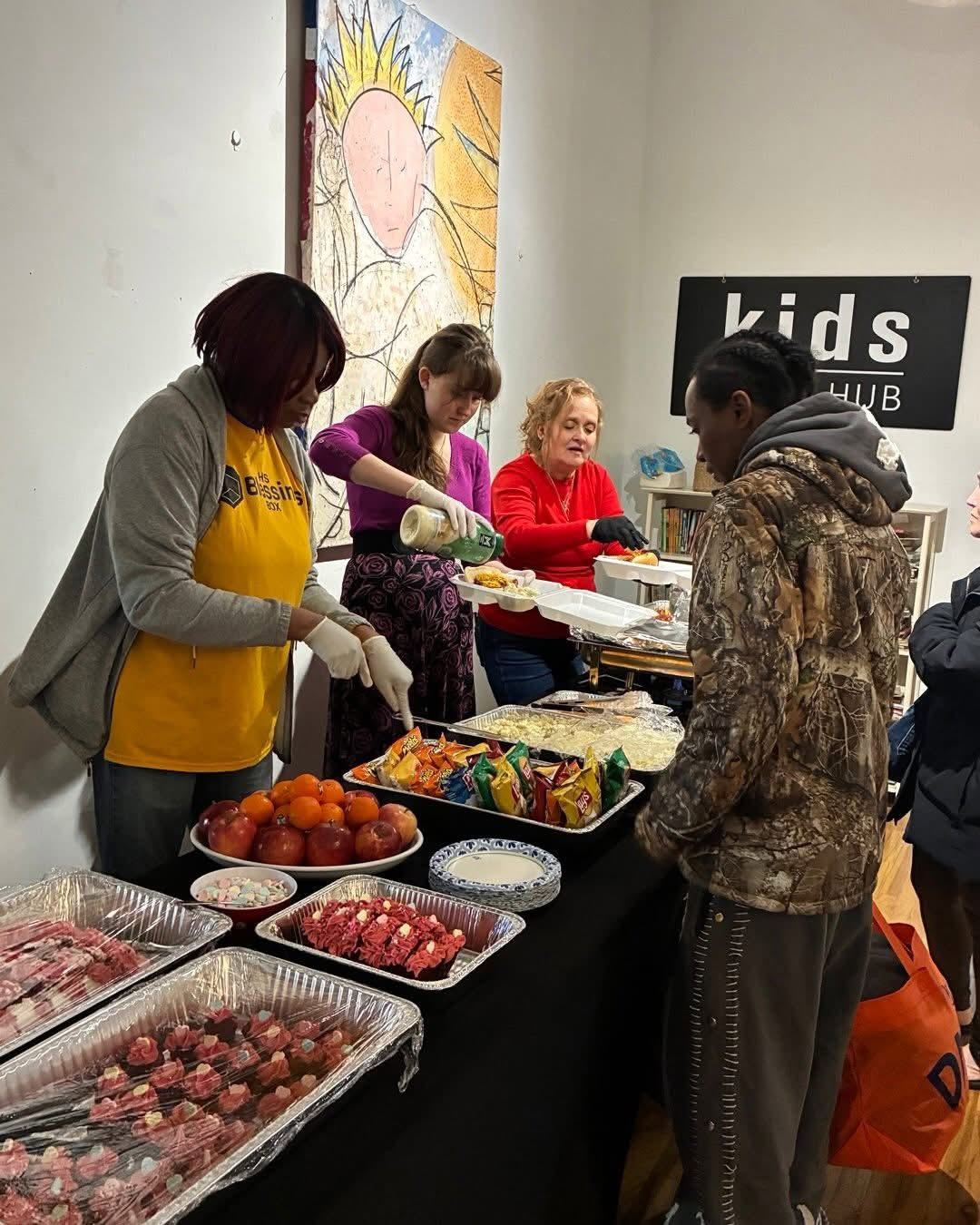 Volunteers serving plates along a buffet line at the Friday community meal