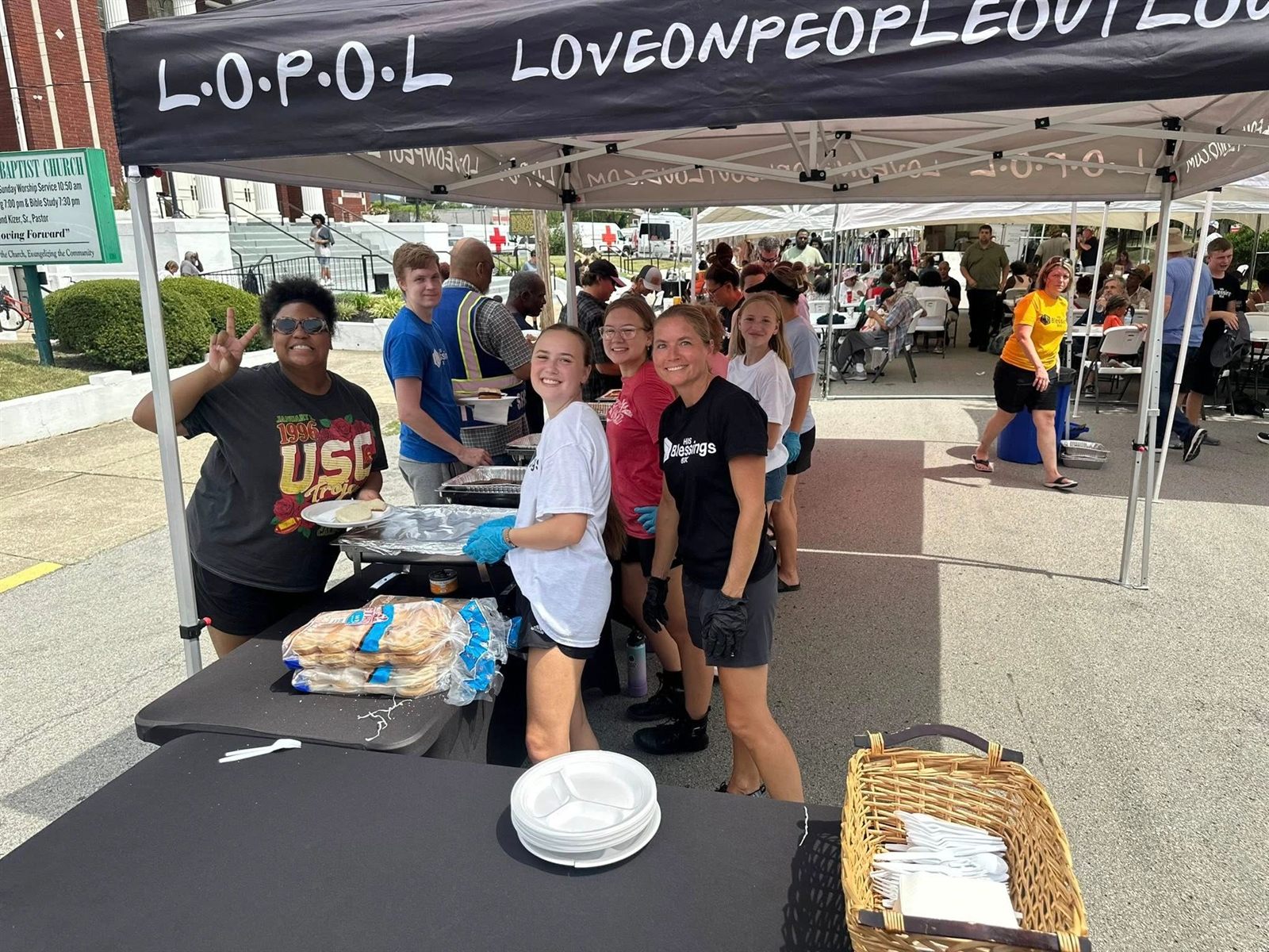 His Blessings Box volunteers serving plates of food under a tent at a Louisville community event